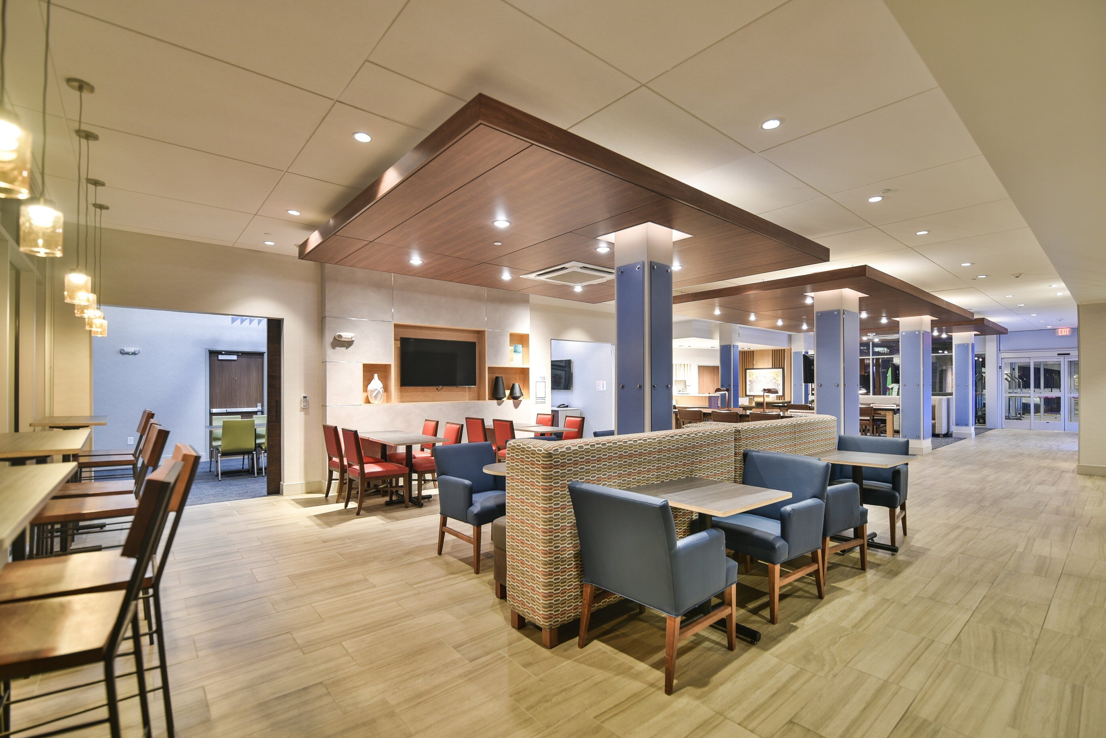 En moderne hotellobby med forskellige siddepladser, herunder borde, stole og bænke.