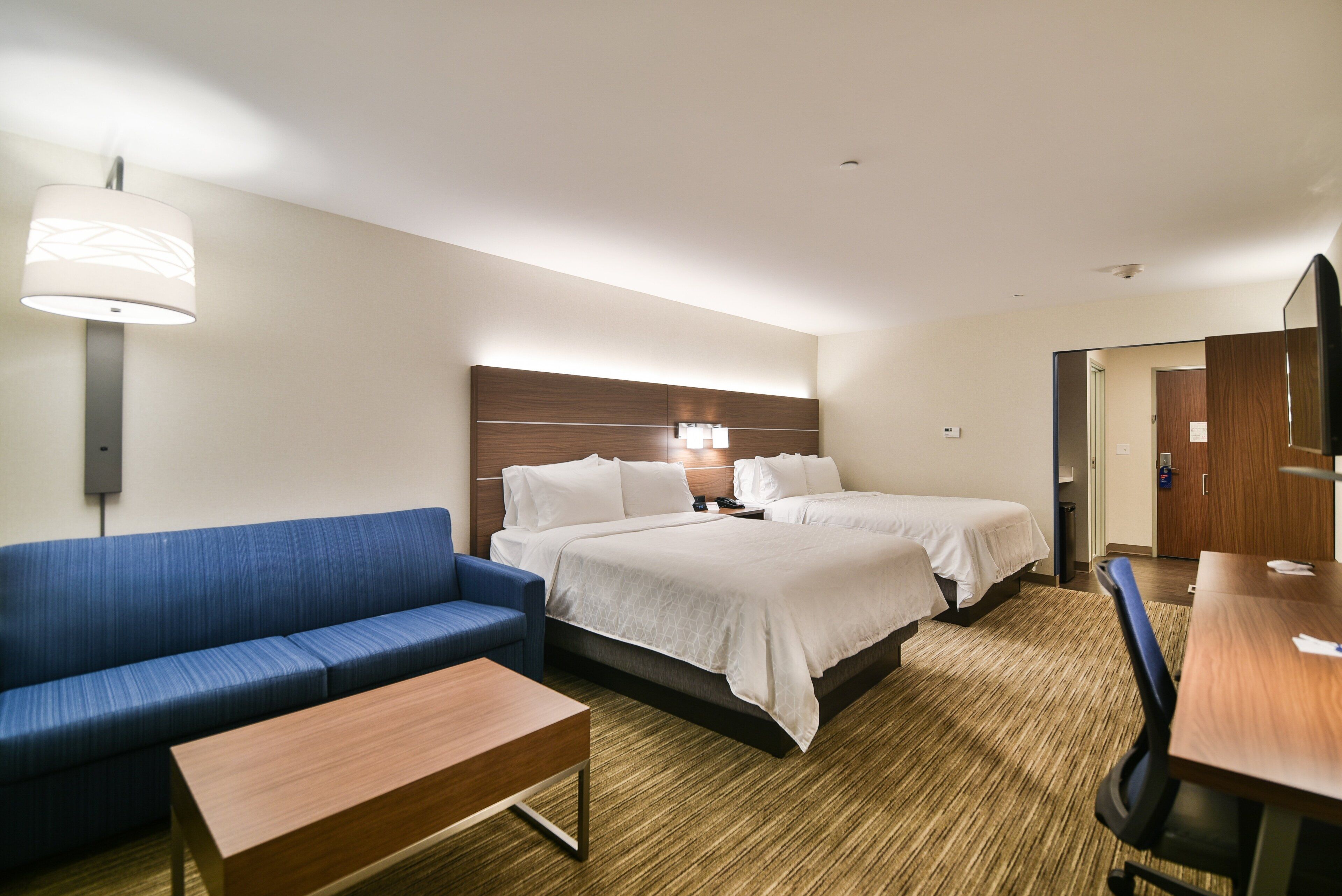 Una habitación de hotel con cama, sofá, escritorio y lámpara.