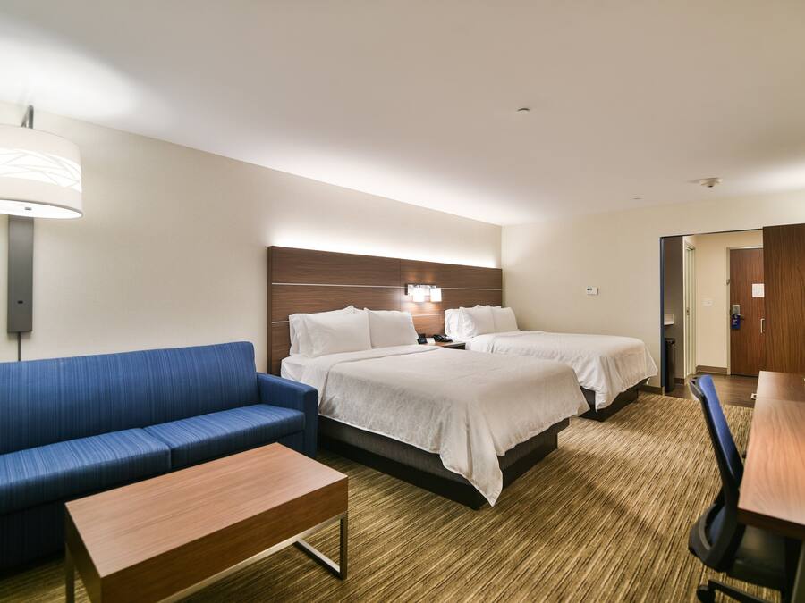 Una habitación de hotel con cama, sofá, escritorio y lámpara.