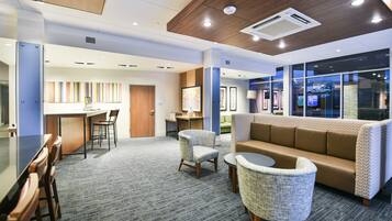 Un moderno vestíbulo de hotel con recepción, zona de estar y un amplio ventanal con vistas.