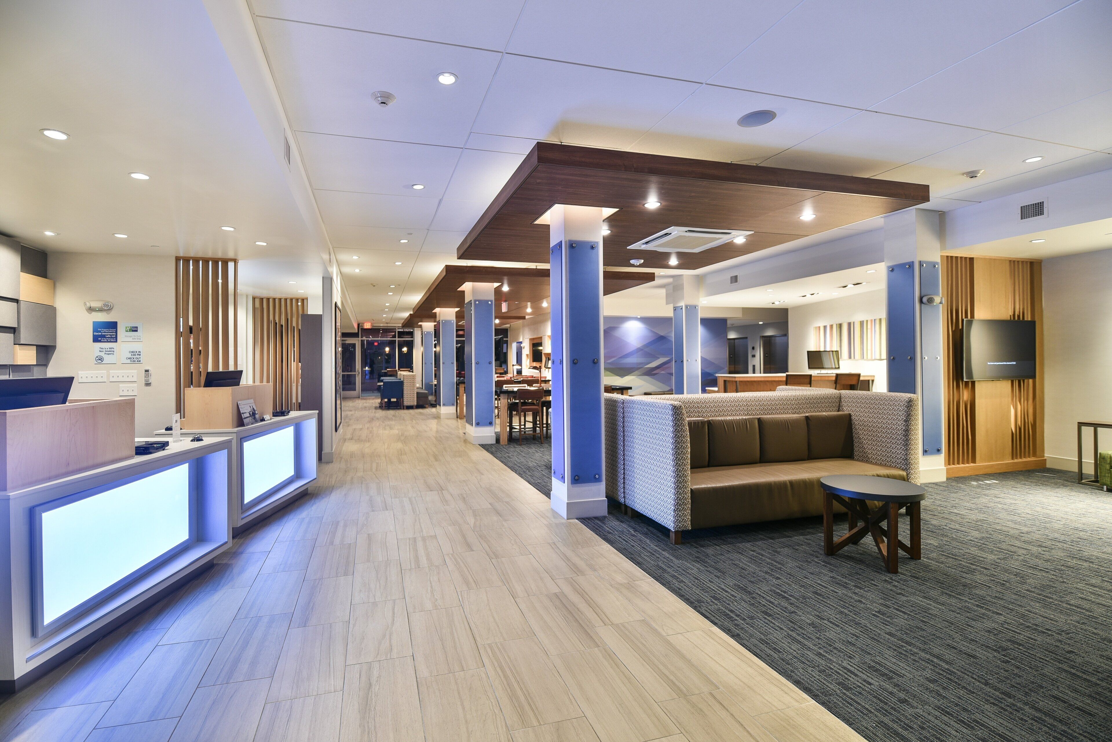 Un moderno vestíbulo de hotel con mostrador de recepción, zona de estar y televisor.