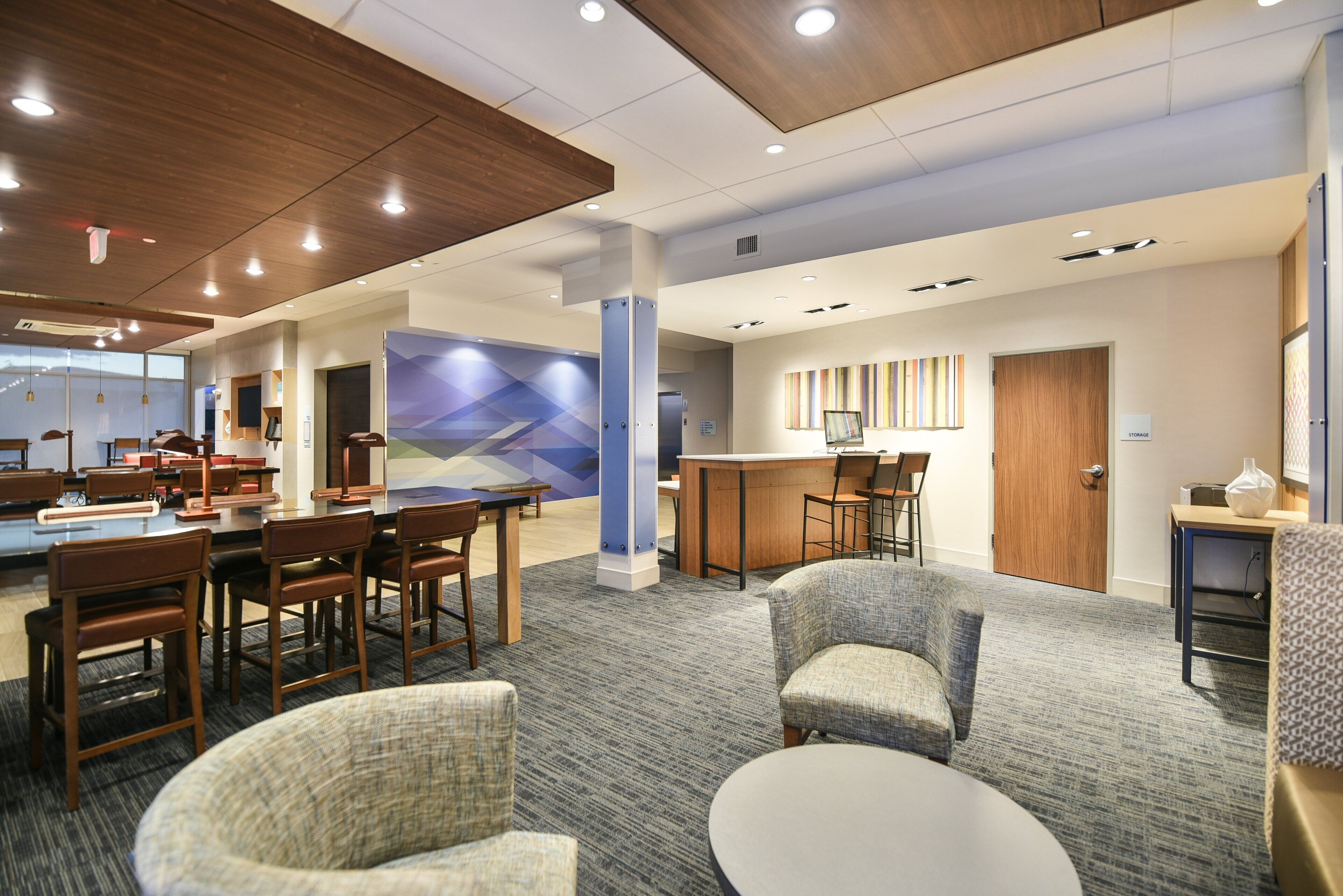 A hotel lobby with a reception desk, seating area, and a large window.