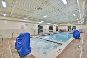 Piscina interior com água cristalina, bordas azulejadas e área coberta com cadeira de salva-vidas.