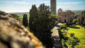 Un bâtiment historique doté d’une haute tour, entouré d’arbres et d’un jardin bien entretenu.