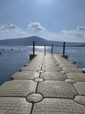 A pier leading to a body of water with a mountain in the background. - Cottage Beach Vico (Caprarola)