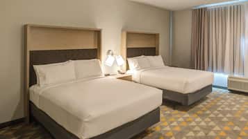 Una habitación de hotel con dos camas, piso estampado y una ventana con cortinas.