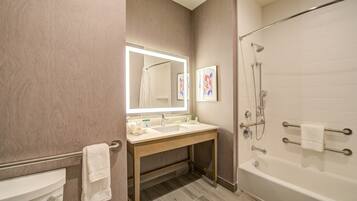 A modern bathroom with a vanity, mirror, sink, and bathtub.