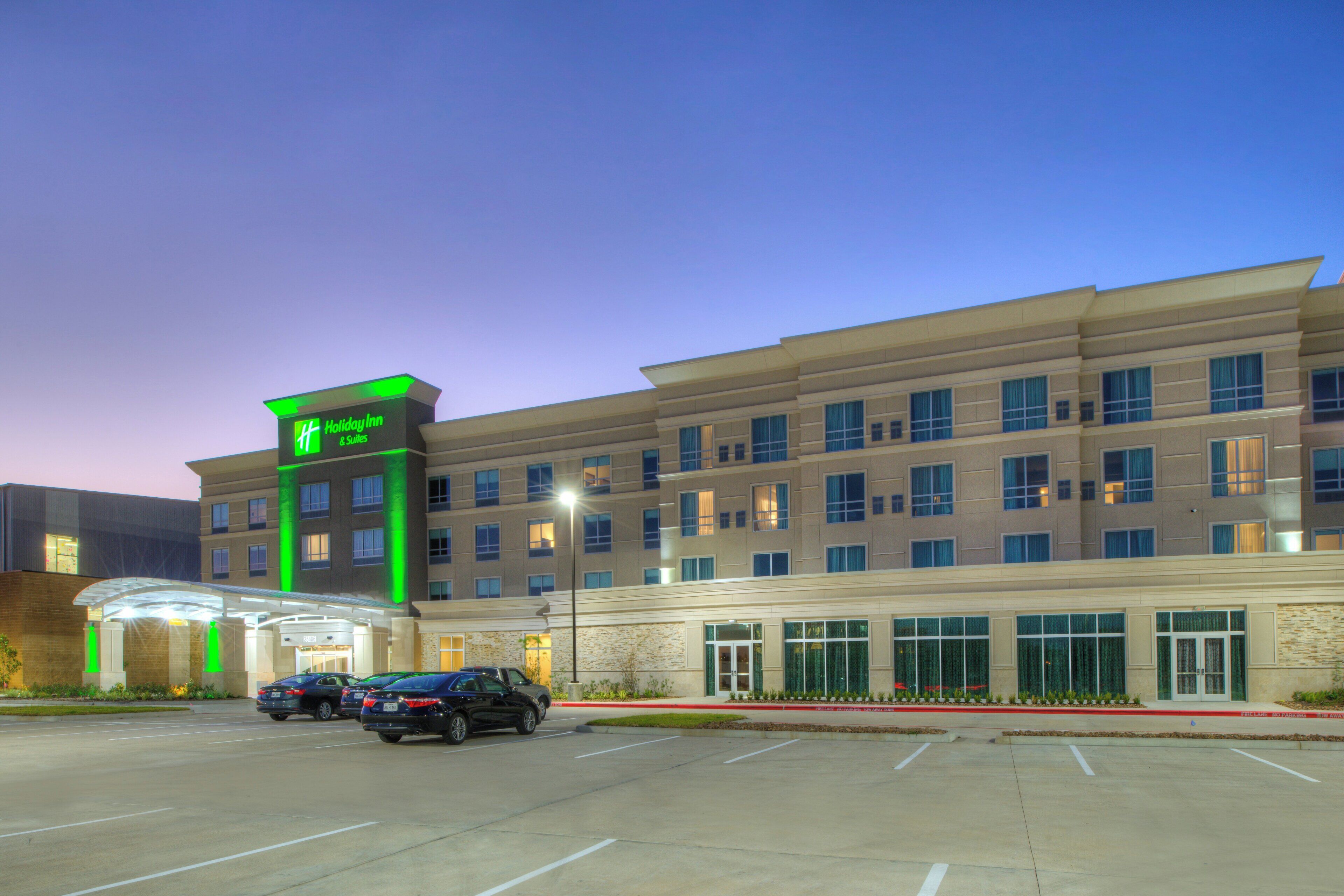Un hotel de varios pisos con un letrero verde llamativo que indica que es un Holiday Inn & Suites.