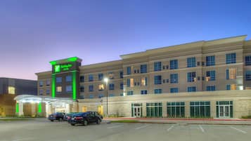 Un hotel de varios pisos con un letrero verde llamativo que indica que es un Holiday Inn & Suites.