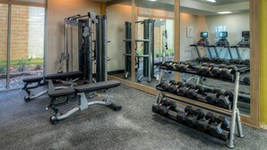 A gym with exercise equipment, treadmills, and a rack of dumbbells.