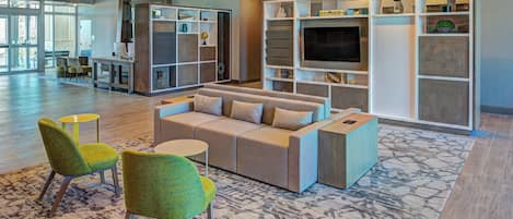 A modern living area with a sofa, two armchairs, a coffee table, and a TV.
