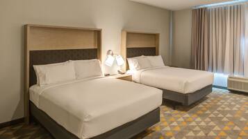 Two single beds with headboards, a nightstand with a lamp, and a patterned carpet.