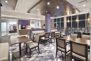 Un hall d’hôtel comprenant des espaces de détente, un coin café et un comptoir d’accueil.