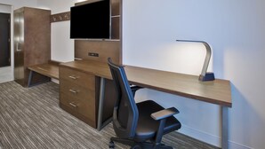 A modern hotel room with a wooden desk, a flat-screen TV, a desk lamp, and a black office chair. - Holiday Inn Express & Suites Okemos - University Area by IHG (Okemos)