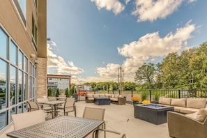 An outdoor patio area with seating and tables, a fire pit, and a view of the surrounding area.