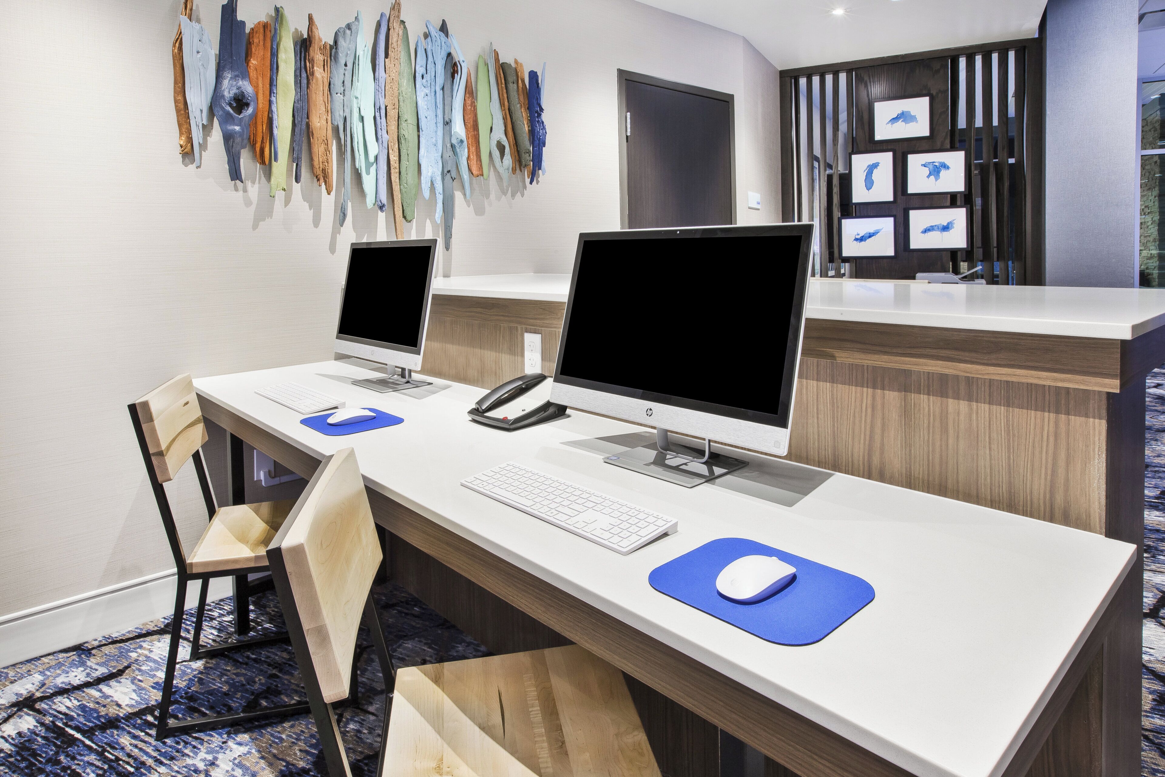 Una recepción de hotel con dos computadoras de escritorio, un teléfono y un teclado.