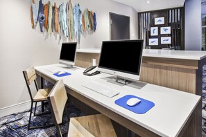 Un comptoir d’accueil d’hôtel équipé de deux ordinateurs de bureau, d’un téléphone et d’un clavier.