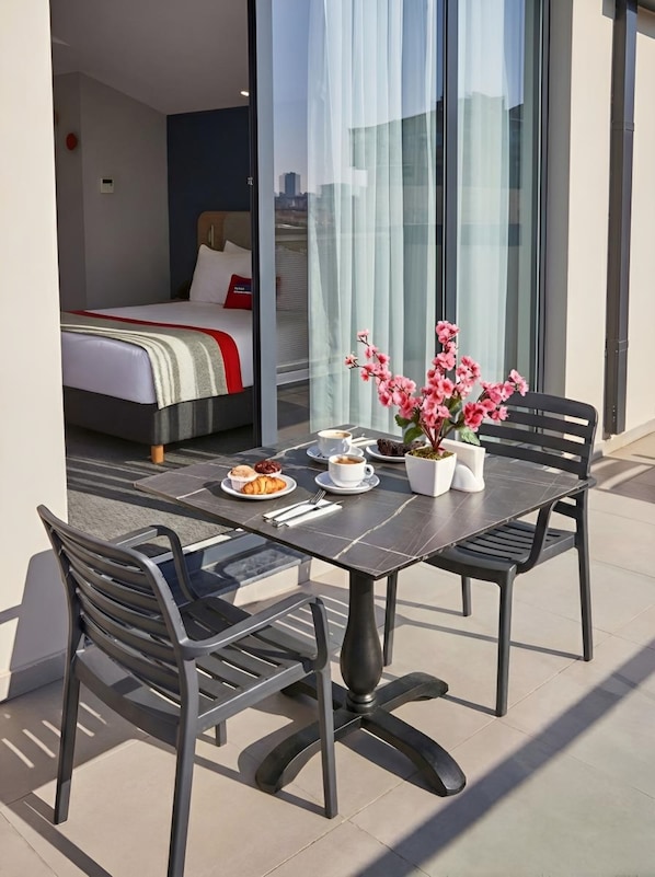 A dining table with chairs, a bed, and a window with curtains.