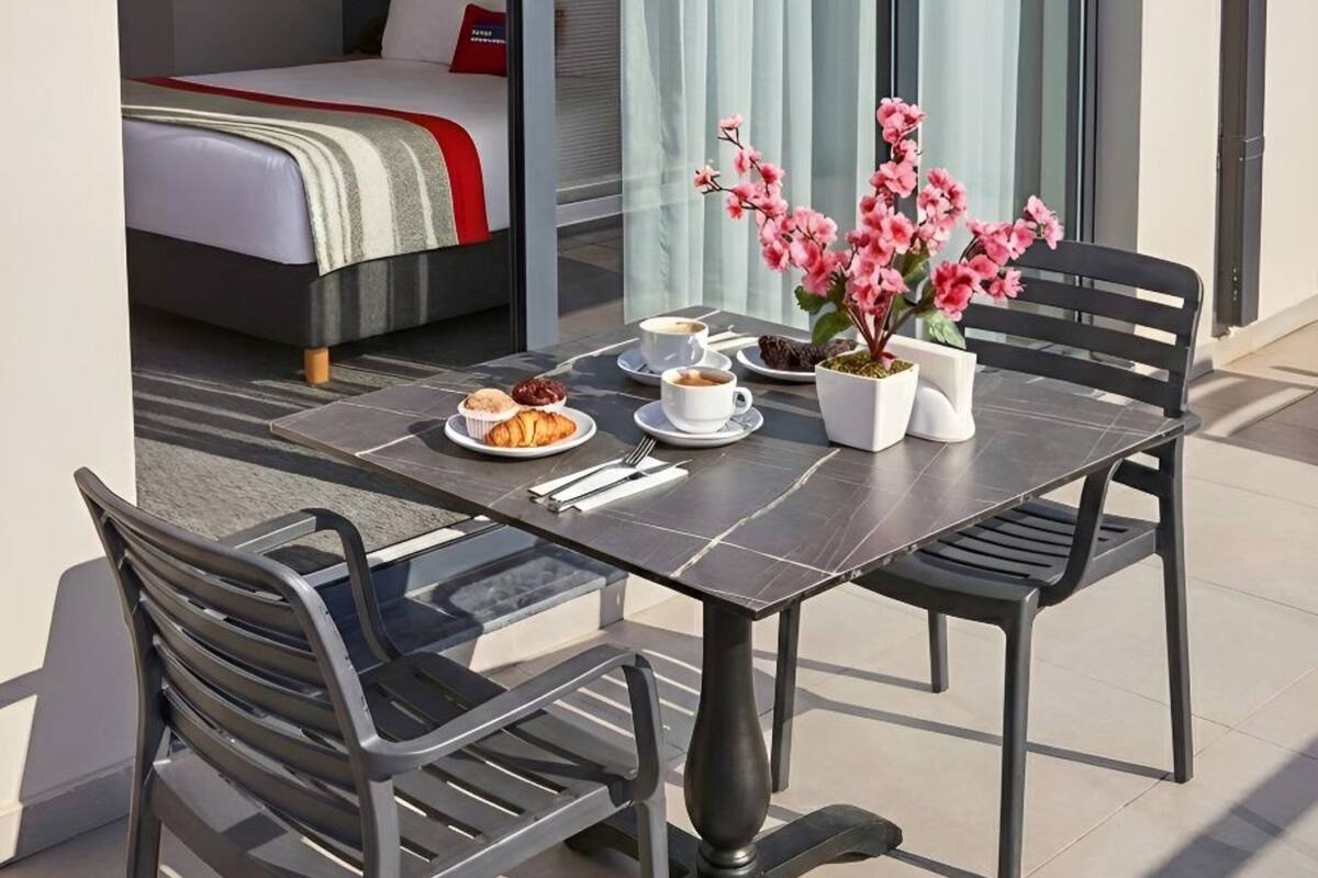A modern outdoor dining area with a table, chairs, and a potted plant.