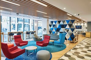 A modern interior with seating areas, a patterned floor, and a television screen. - Holiday Inn Express Istanbul - Atakoy Metro by IHG (Istanbul)