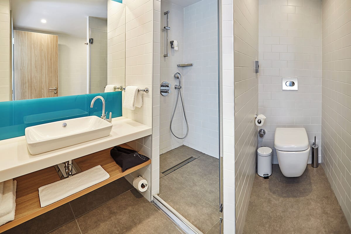 A modern bathroom with a glass-enclosed shower, a white sink, and a toilet.