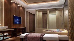 Un baño moderno con una bañera grande, un tocador con espejo y un televisor montado en la pared.