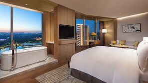 A modern hotel room with a large bed, a bathtub, a flat-screen TV, and a city view.