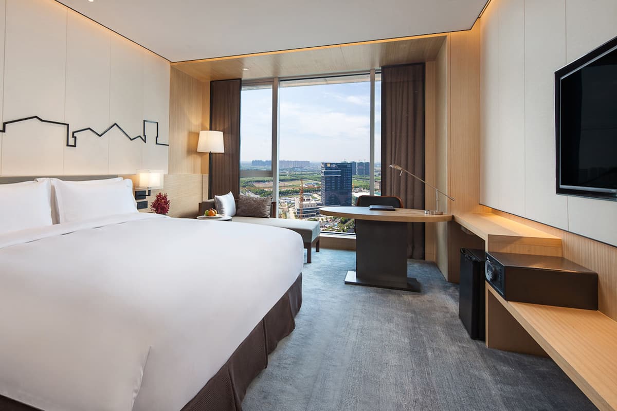 Een moderne hotelkamer met een groot bed, een bureau en een televisie.