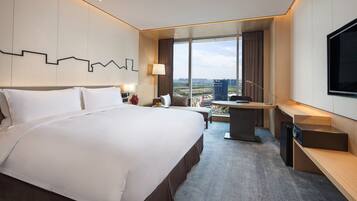 Una habitación de hotel moderna con una cama grande, un escritorio y un televisor.