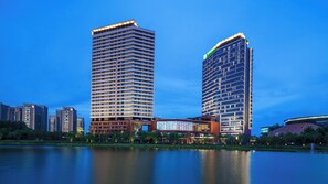 Two high-rise buildings with a reflective water body in the foreground.