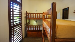 A bunk bed room with a wooden headboard, a small desk, and a window with blinds. - Mandala Hostel (Jijoca de Jericoacoara)
