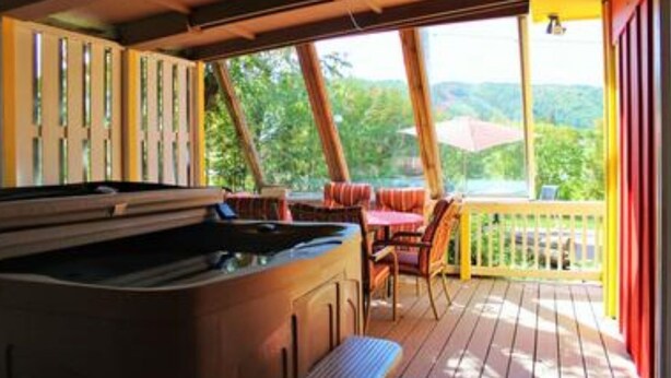 A hot tub on a wooden deck with outdoor seating and a view of greenery. - 3 Bed Blue Mountain Cottage with Hot Tub (The Blue Mountains)