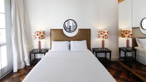 A hotel room with a large bed, two bedside tables with lamps, a round mirror above the bed, and a window with curtains. - Rio107 - Apartment Copacabana 2 Bedrooms (Rio de Janeiro)