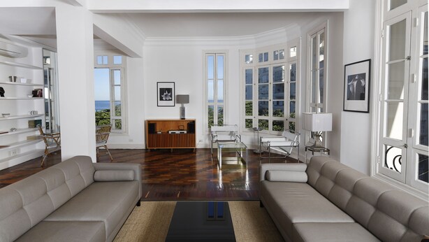 A spacious living room with a large sofa set, a coffee table, and a view of the outdoors through large windows. - Rio107 - Apartment Copacabana 2 Bedrooms (Rio de Janeiro)