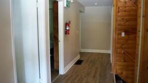A hallway with wooden flooring, white walls, and a wooden door. - 6 Bed Blue Mountain Chalet with Hot Tub 8 (The Blue Mountains)