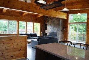 Ein Ferienhausinnenraum mit Kamin aus Stein, Holzwänden, einer Couch und einem Essbereich.