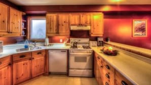 A kitchen with wooden cabinets, a stainless steel sink, a stove, and a refrigerator. - 6 Bed Blue Mountain Executive Chalet with Hot Tub 157 (The Blue Mountains)