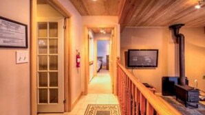 A hallway with wooden flooring, a wooden railing, and a television mounted on the wall. - 5 Bed Blue Mountain Luxury Chalet with Hot Tub 159 (The Blue Mountains)