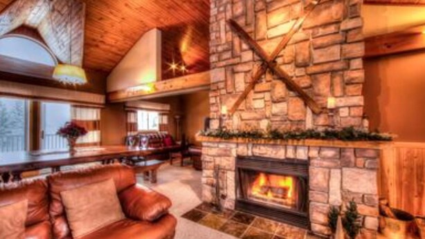 A cozy living room with a stone fireplace, leather sofa, and a wooden ceiling. - 5 Bed Blue Mountain Luxury Chalet with Hot Tub 159 (The Blue Mountains)