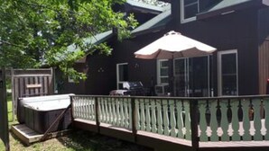 Una casa con un porche techado, un patio cercado y un jacuzzi.