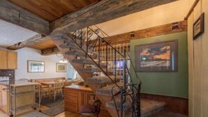 Un interior rústico con una escalera de madera, una zona de comedor y una cocina.