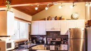 A modern kitchen with white cabinets, a stainless steel refrigerator, and a central island with stools.
