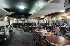 Un restaurante con varias mesas, cabinas, una zona de bar y una barra con el menú.