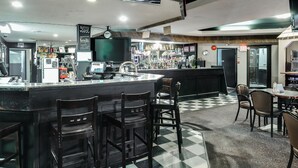 A bar area with a checkered floor, bar stools, a counter with a TV, and various bottles and glasses. - Adobe Inn (Martensville)