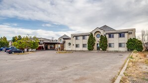 A multi-story building with a parking lot in front. - Adobe Inn (Martensville)
