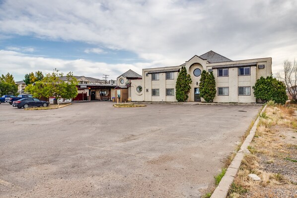 A multi-story building with a parking lot in front. - Adobe Inn (Martensville)