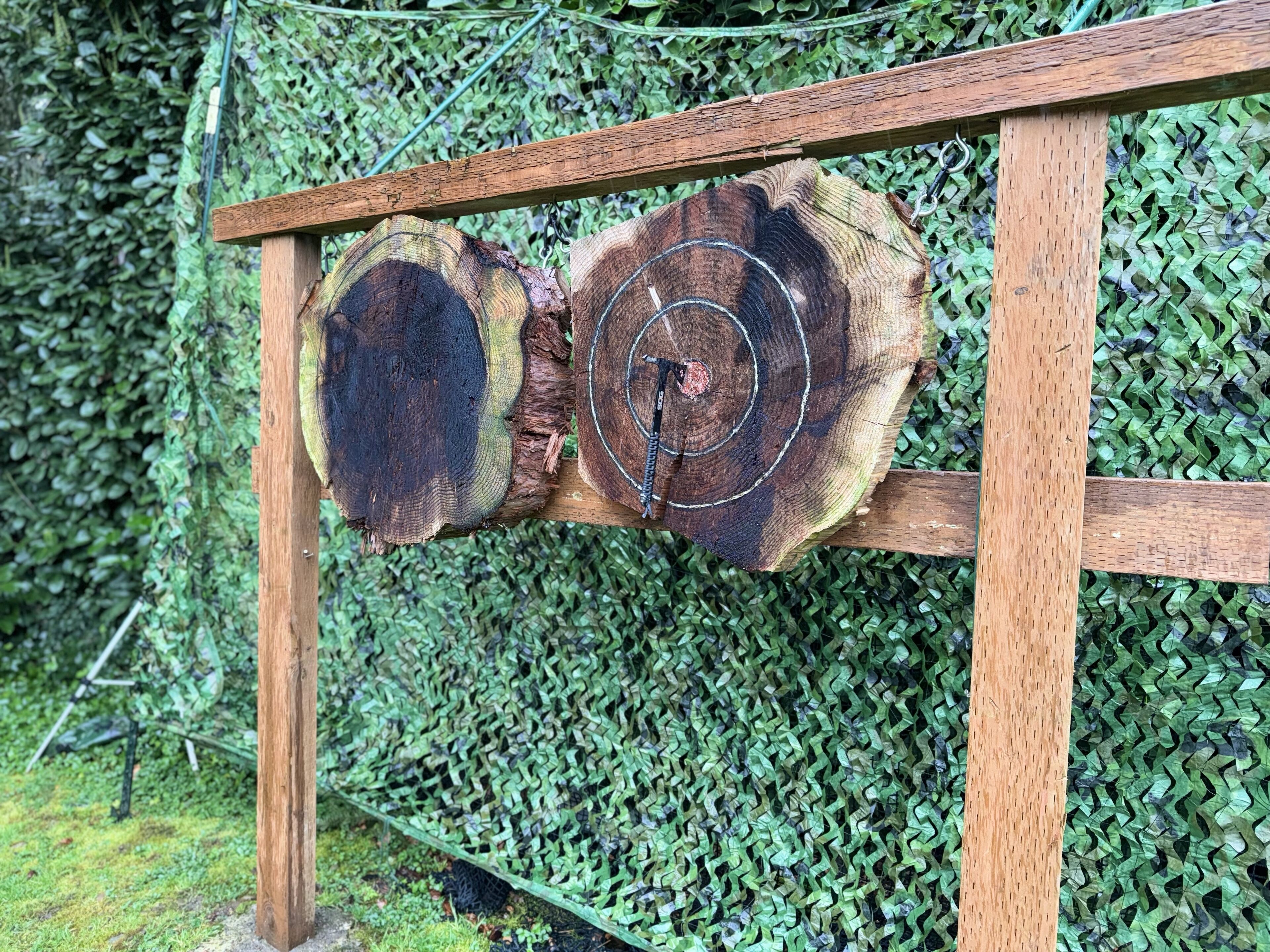 A wooden structure with two large tree trunks mounted on a wooden frame, set against a background of green foliage.