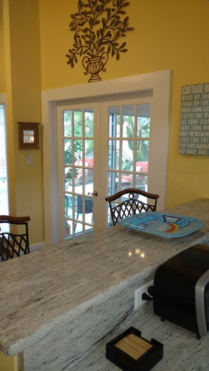 Enjoy a room with a marble countertop, a black chair, and a door leading to an outdoor area with seating.