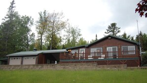 En toetages hytte med veranda foran og garage.
