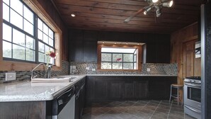 A modern kitchen with dark wood cabinets, a large window, and a tiled backsplash.